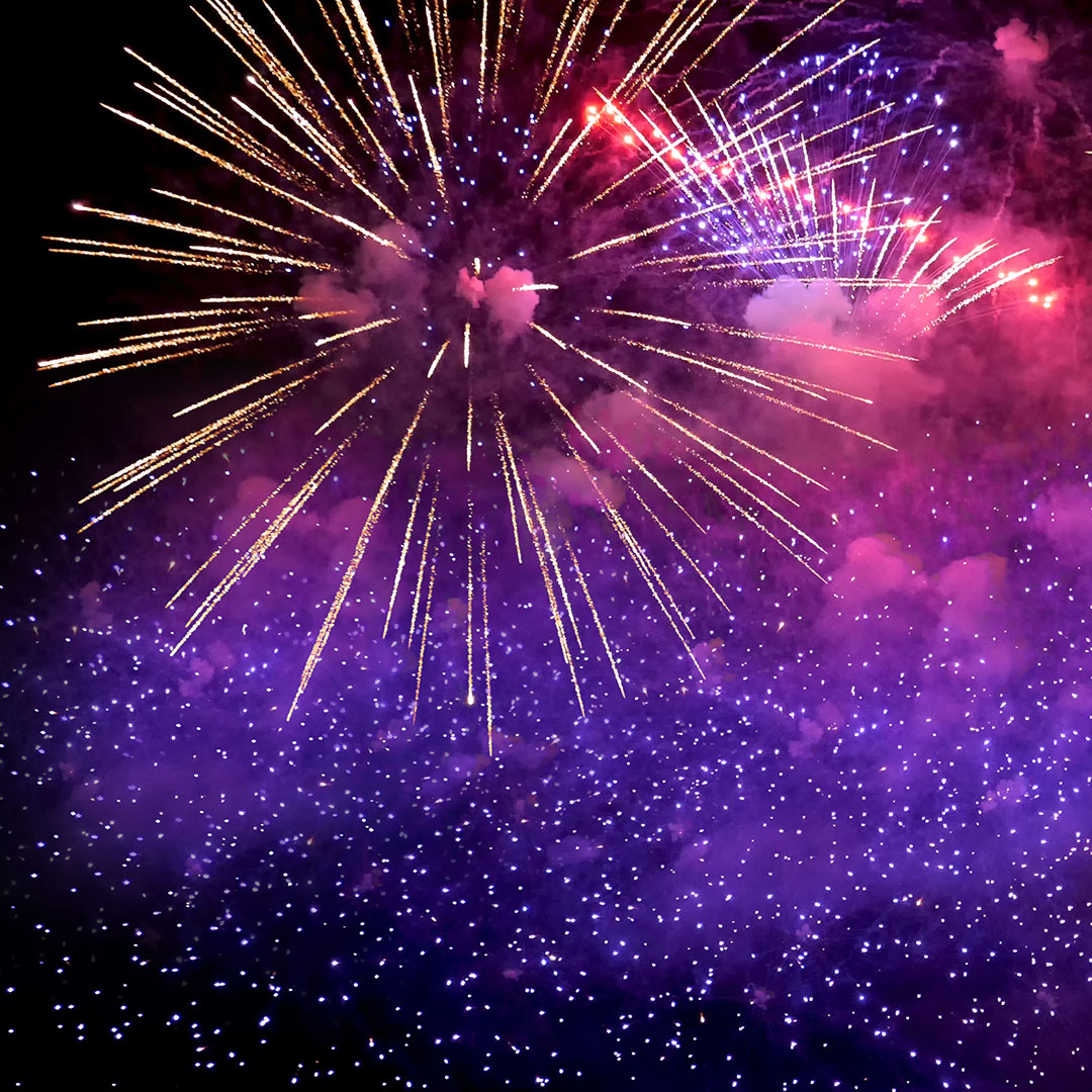 Ein buntes Feuerwerk im Nachthimmel in den Farben lila, pink und gold