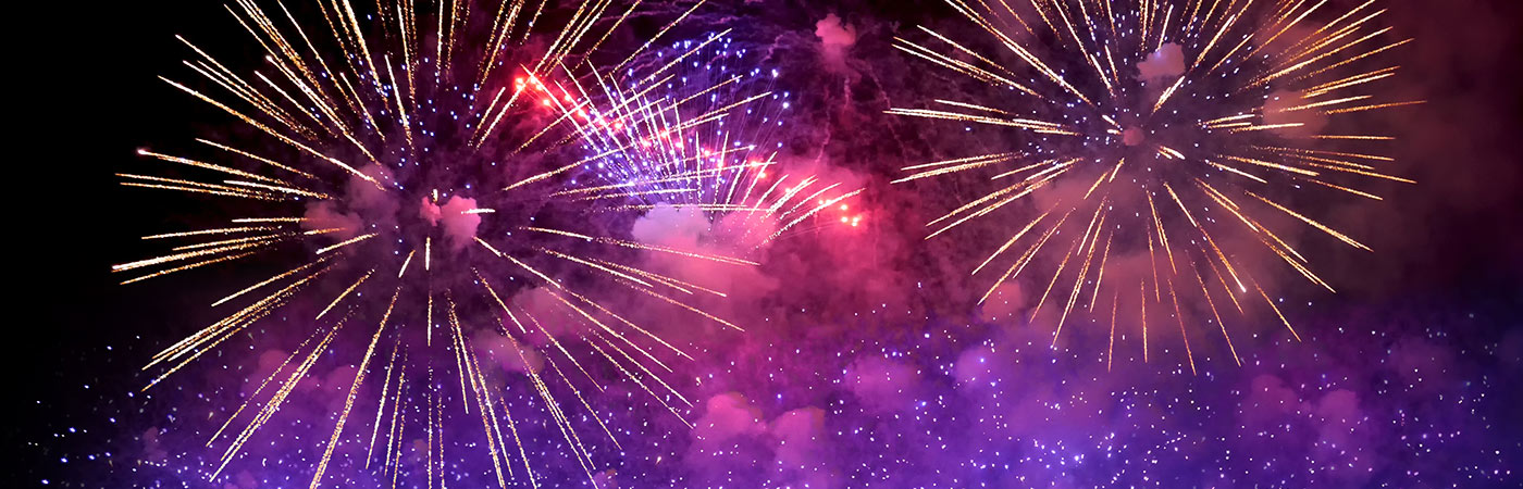 Ein buntes Feuerwerk im Nachthimmel in den Farben lila, pink und gold