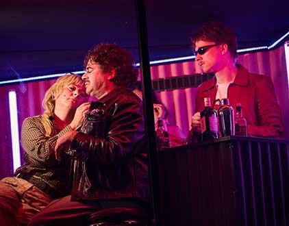 Zwei Menschen sitzen an der Bar und eine Person steht hinter der Bar.