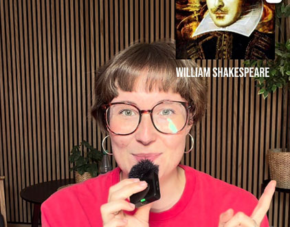 Dramaturgin Sophie Hein, mit Mikrofon in der Hand, zeigt auf ein Bild von William Shakespeare