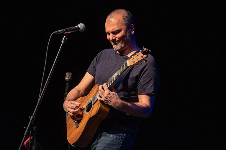 Mann, der eine Gitarre spielt und vor einem Mikrophone steht